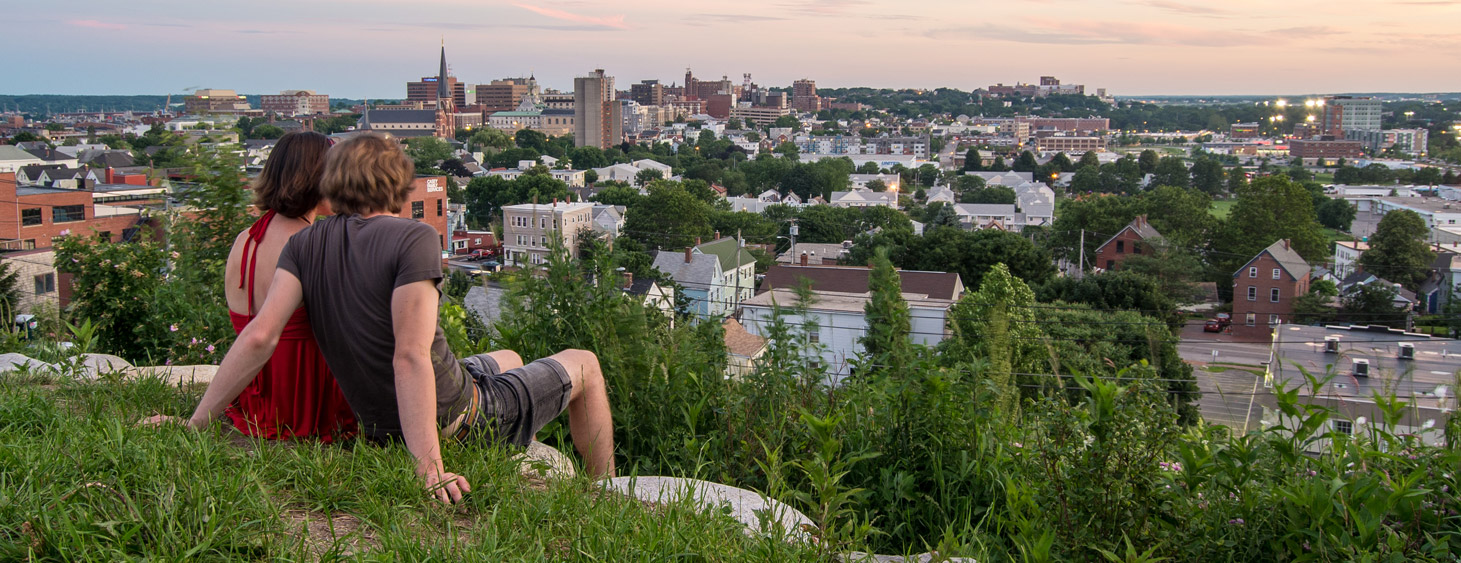 Couple overlooking the city from a hill sitting in the grass